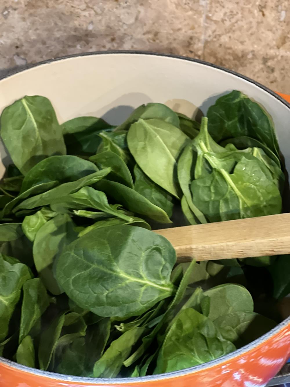 spinach cooking in orange pan on stove