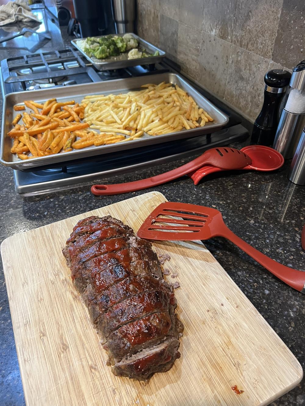 meat loaf, fries, and roasted vegetables on stove