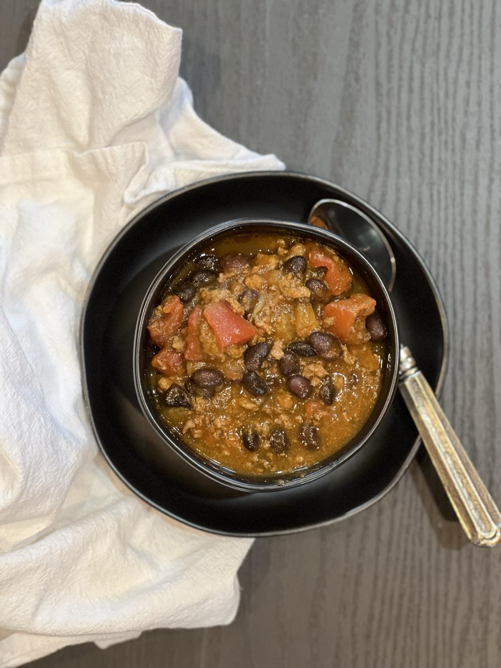 pumpkin chili in black bowl on white napkin