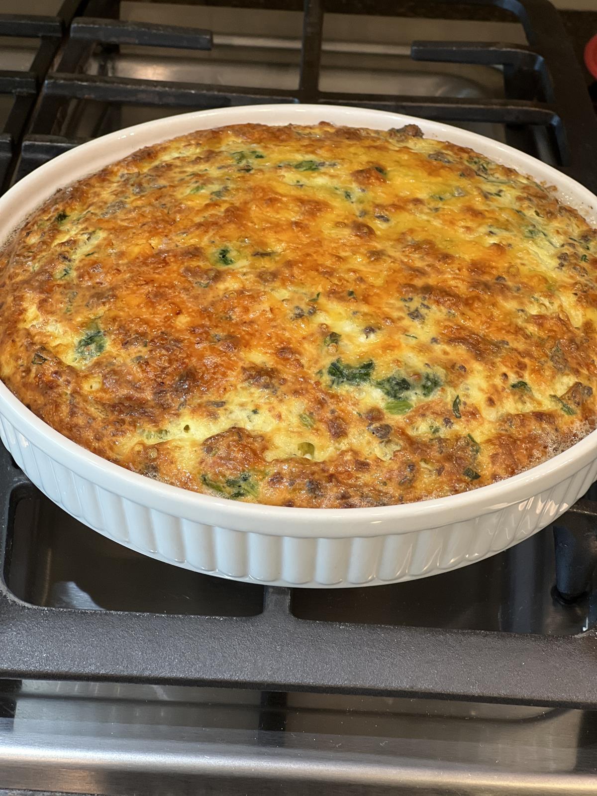 crustless spinach sausage quiche in white dish on stove top