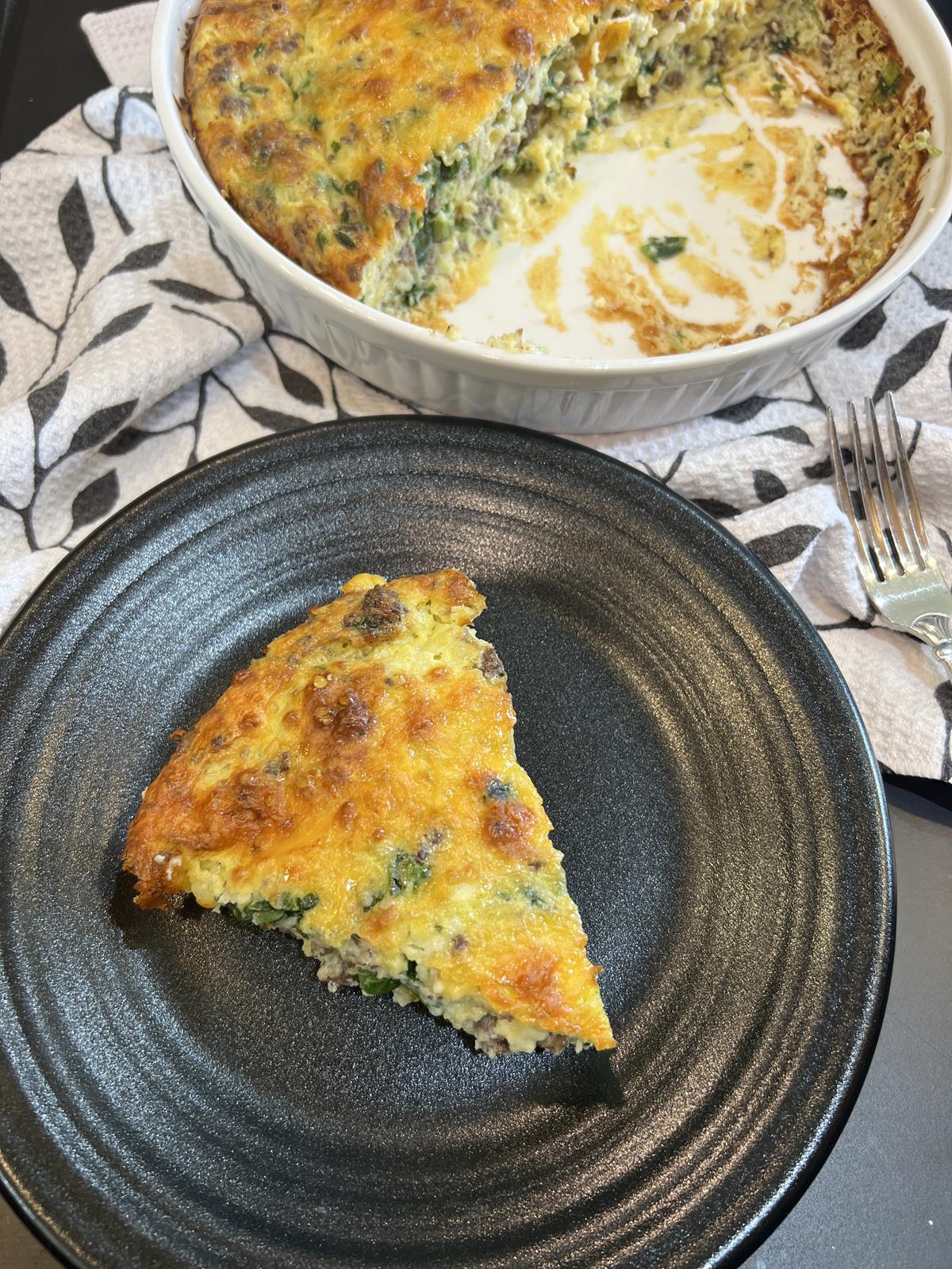 crustless sausage spinach quiche in white dish with a piece on a plate