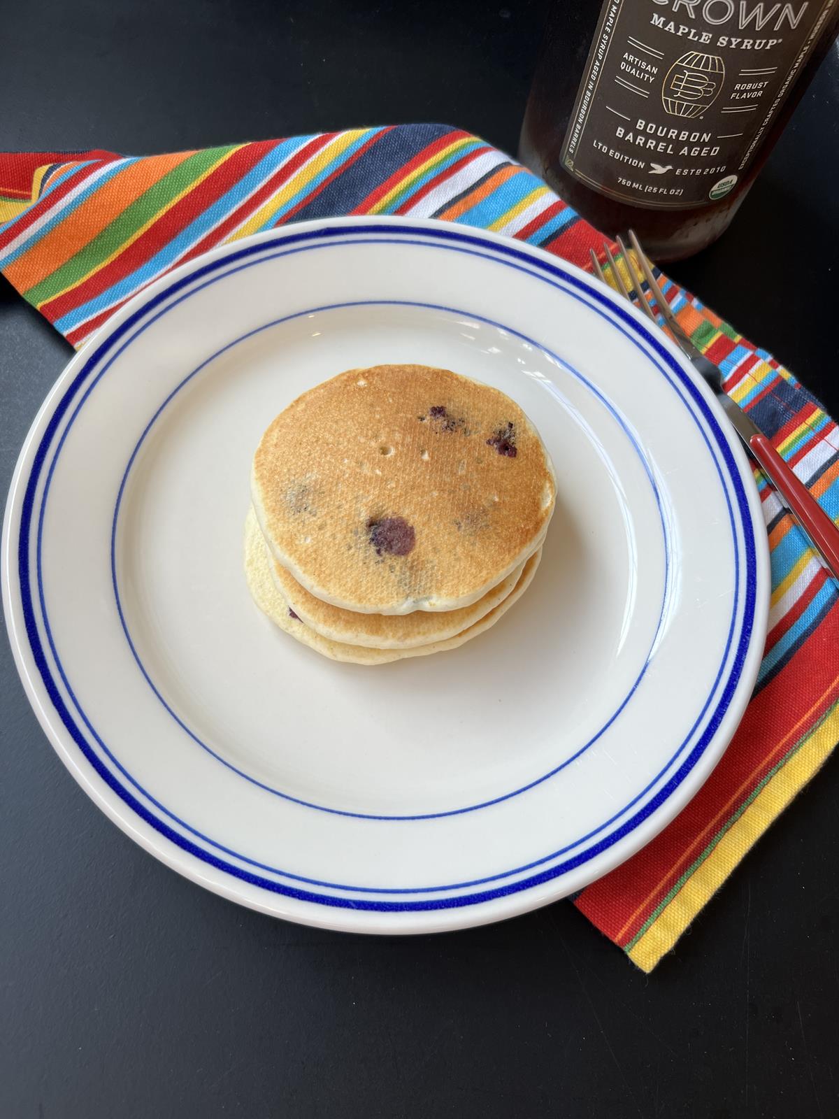 blueberry pancakes on blue and white plate on striped napkin