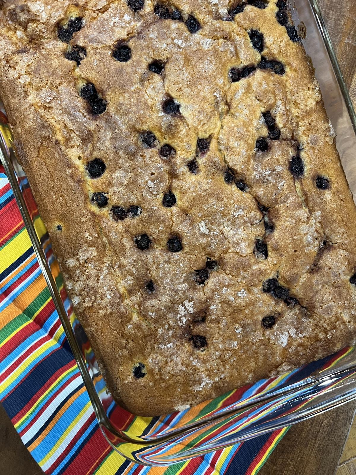 blueberry coffee cake in glass pan on stiped napkin