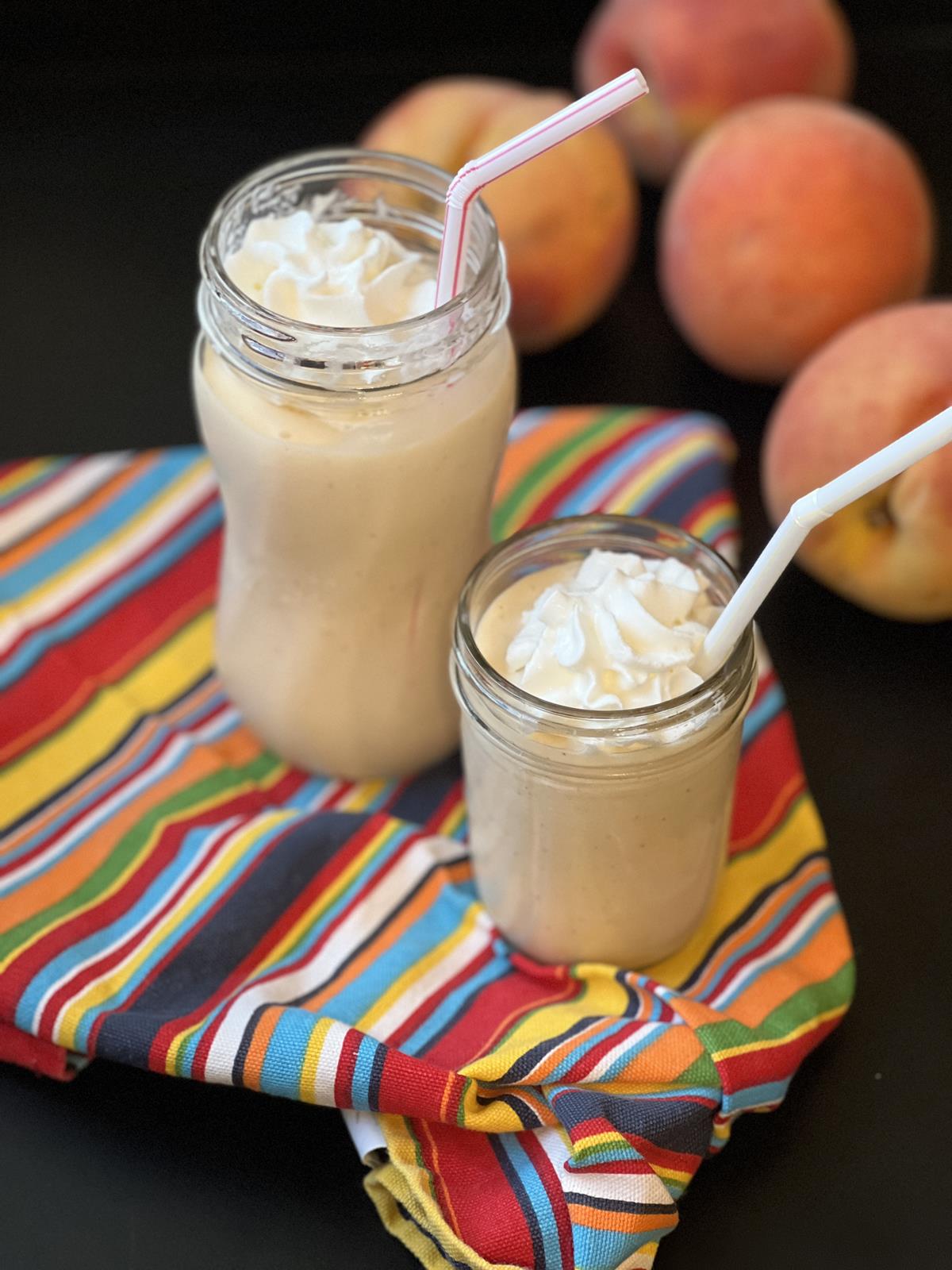 Homemade Peach Milkshakes in glass jar cups and striped napkins
