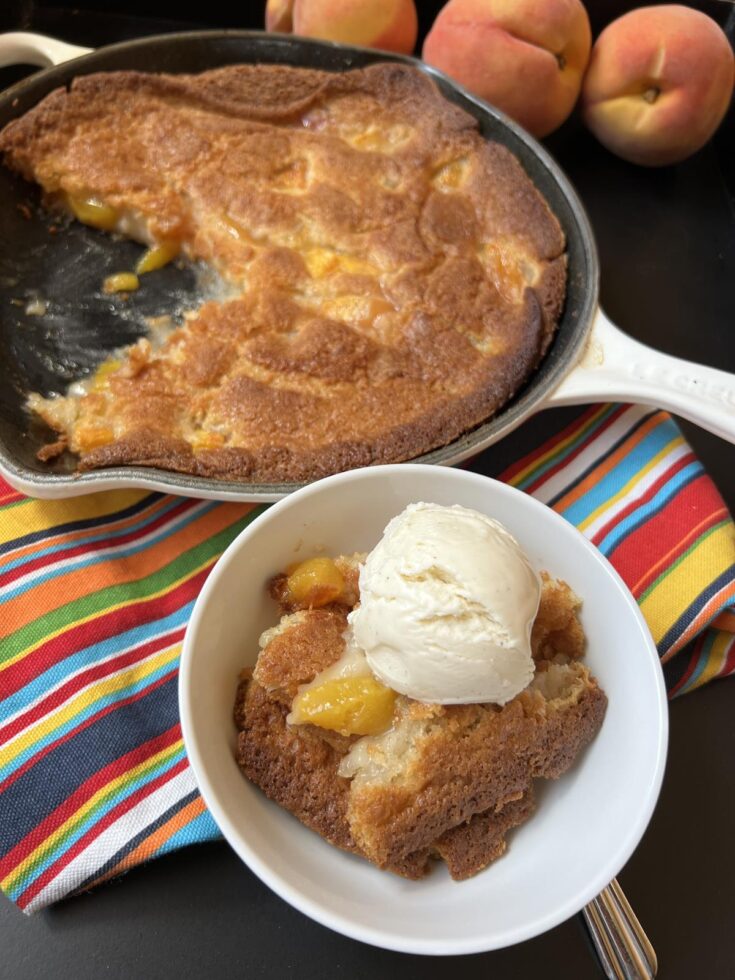 Martha Stewart Peach Buckle with ice cream in white bowl with cobbler in cast iron pan