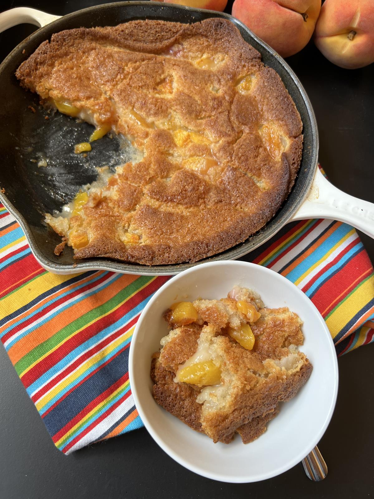 peach buckle in a cast iron skillet and a scoop of cobbler in white bowl