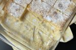 Gluten free lemon bars in glass pan on yellow kitchen towel