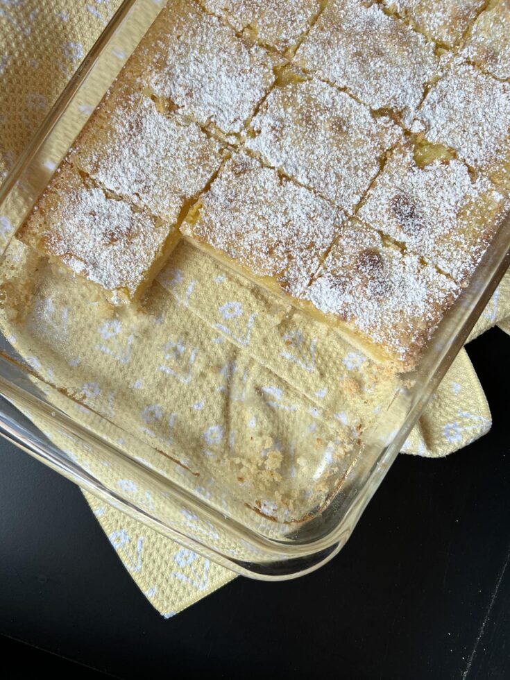 Gluten free lemon bars in glass pan on yellow kitchen towel