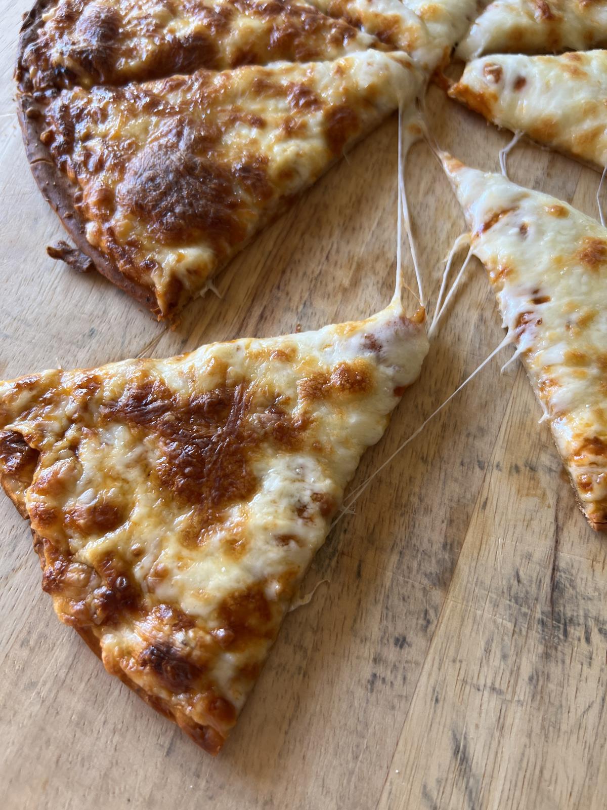 frozen gluten free pizza baked and cut into pieces on cutting board