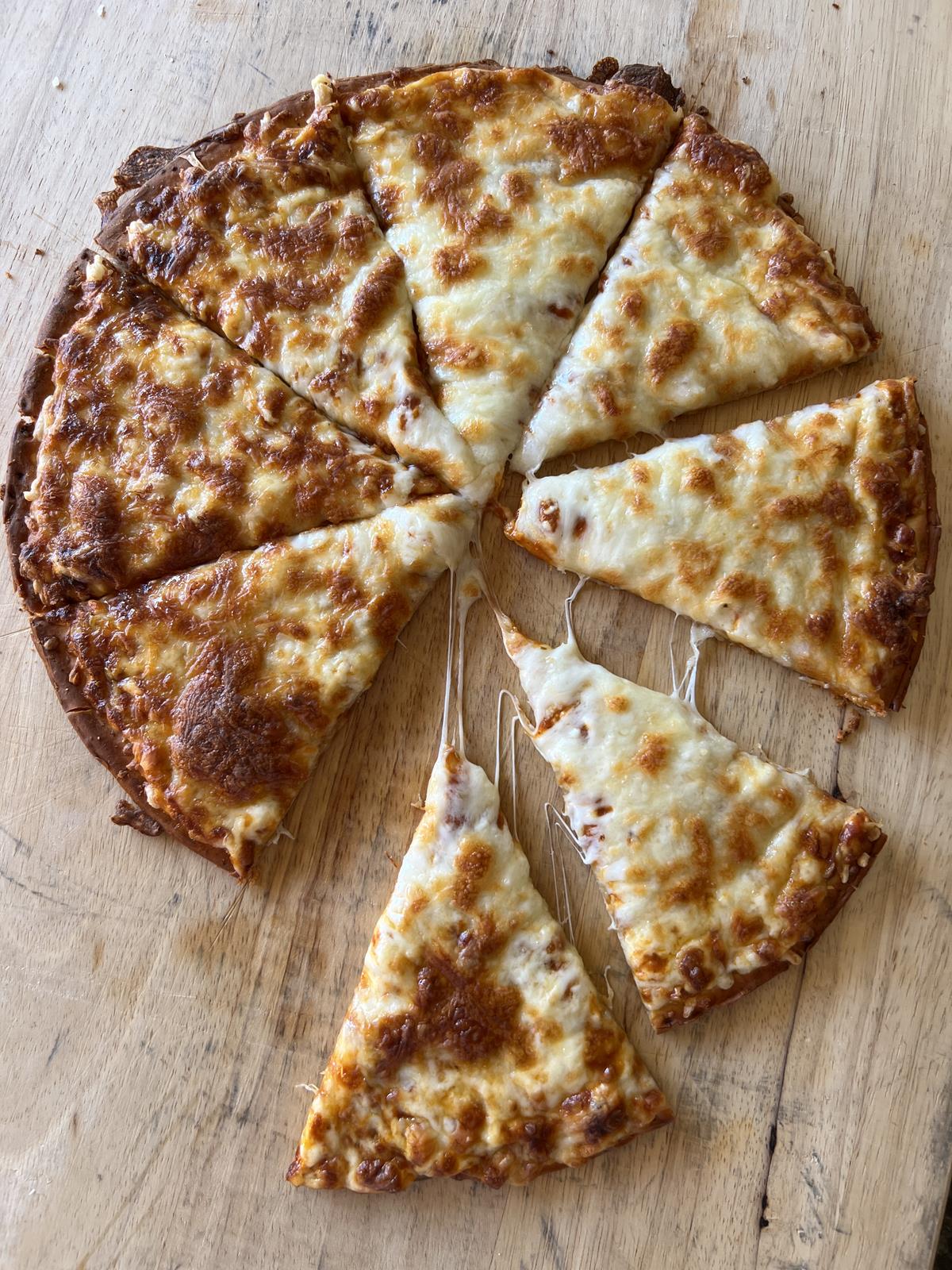 frozen gluten free pizza with cheese cut into pieces on cutting board