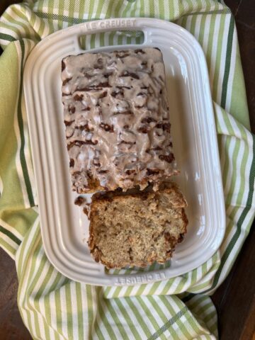 Gluten Free Apple Fritter Bread sliced with glaze on white platter with green and white napkin