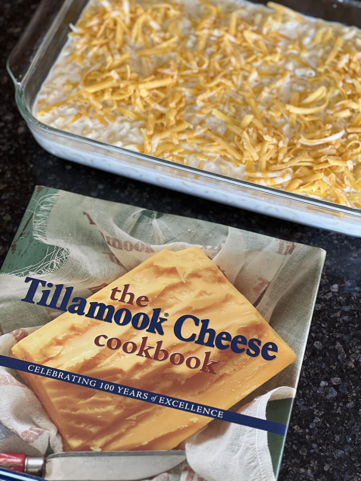 Tillamook Cheese cookbook with pan of unbacked mac and cheese in background