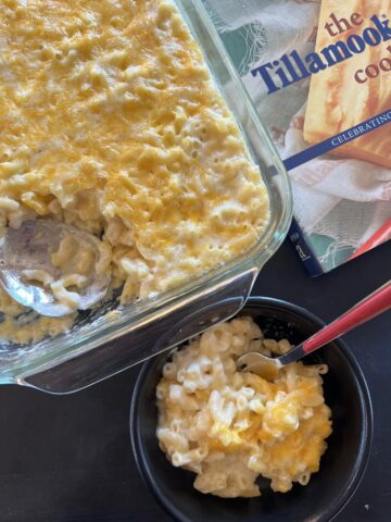 mac and cheese in black bowl with fork and pan fo mac and cheese in background