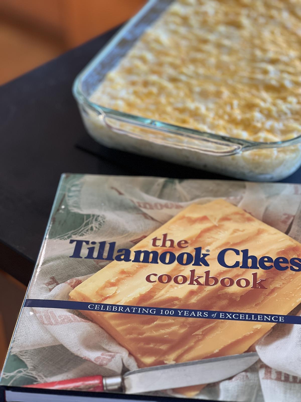 Tillamook Cheese Cookbook with pan of mac and cheese in background