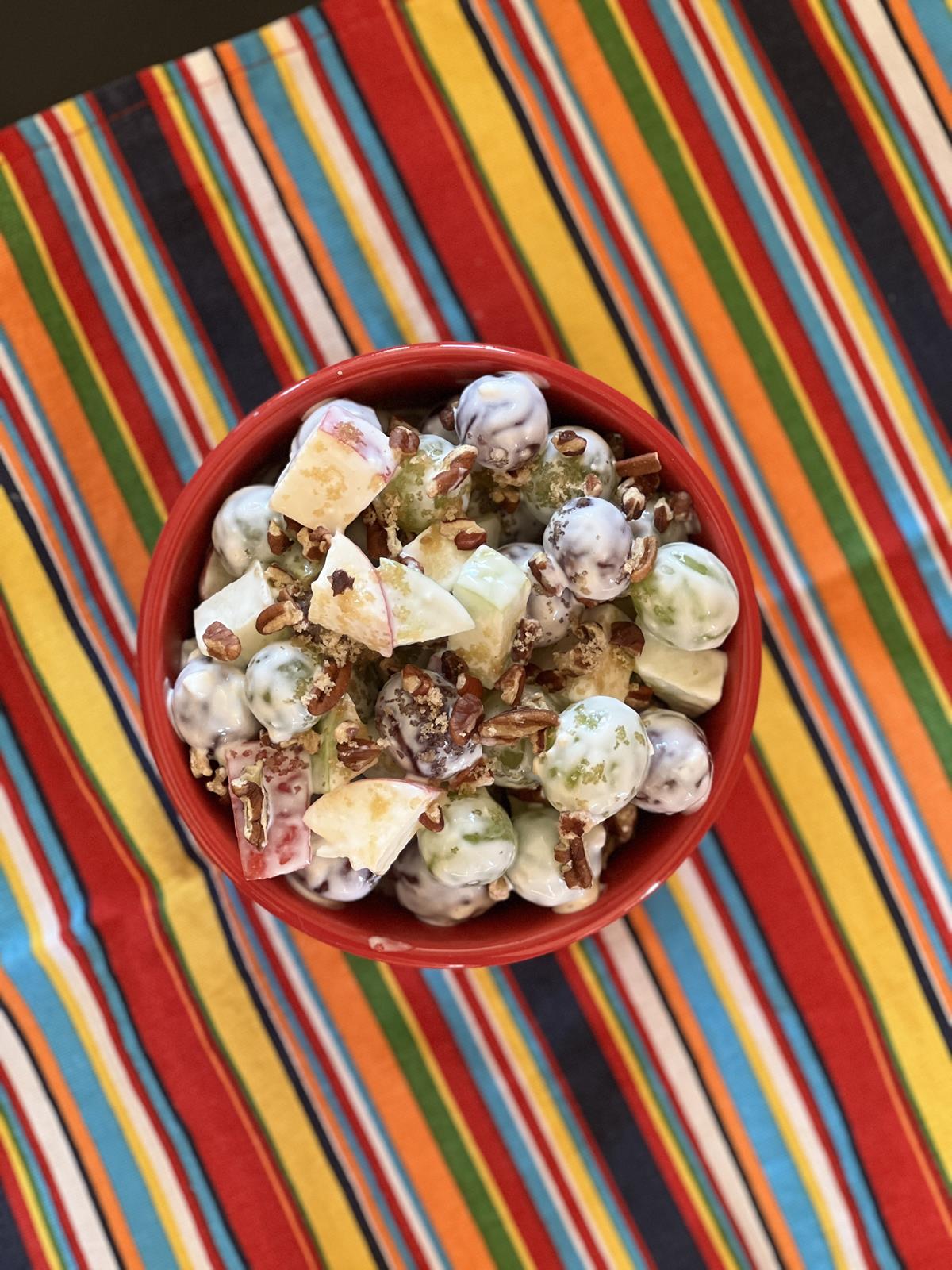 fruit salad with pecans in red bowl on striped napkin