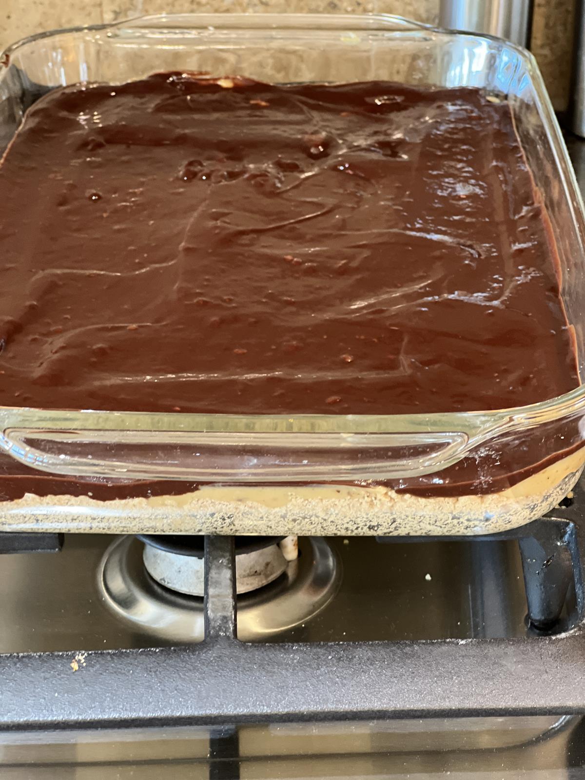 Chocolate Caramel Shortbread Bars layered in glass pan on stovetop