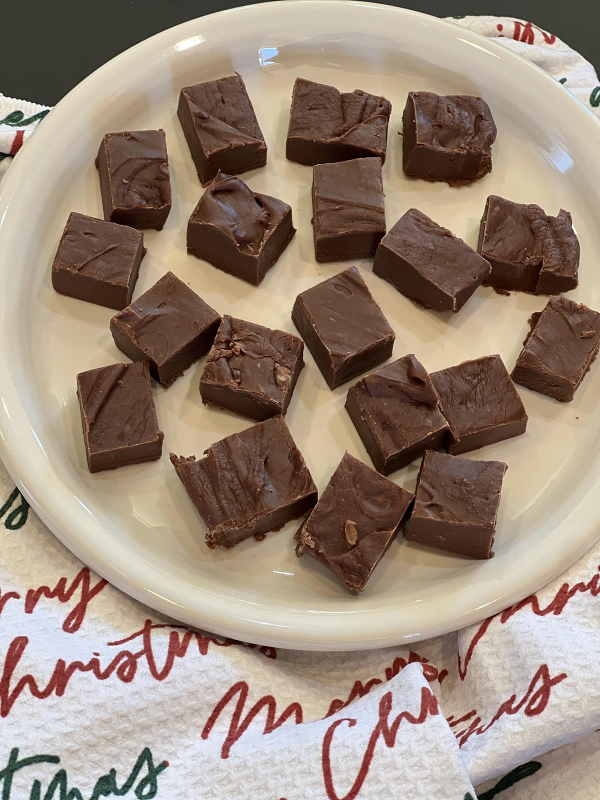 marshmallow fudge on white plate with Christmas napkin in background