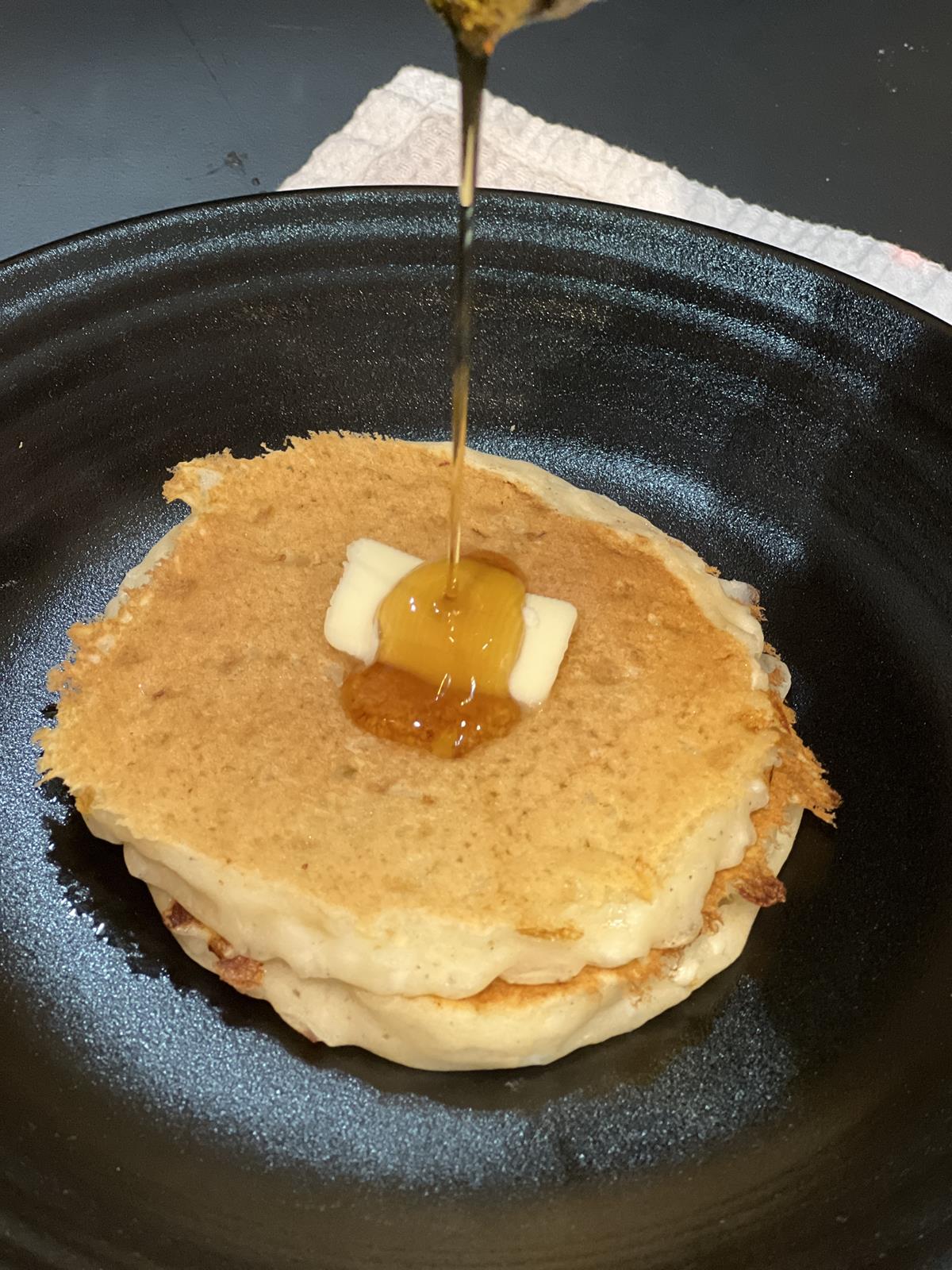 pancakes with butter and syrup on black plate