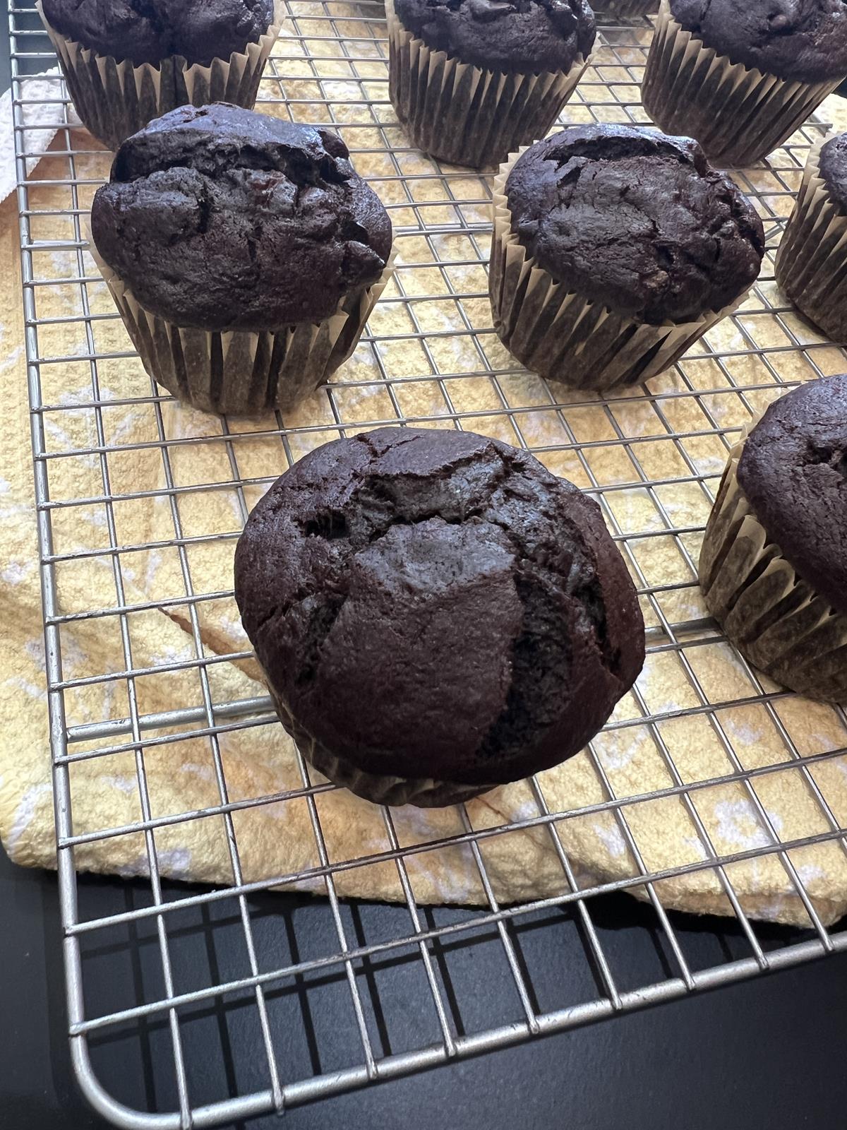 chocolate muffins on a wire cooling rack with yellow towel underneath