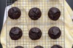 chocolate muffins on a wire cooling rack with yellow towel underneath