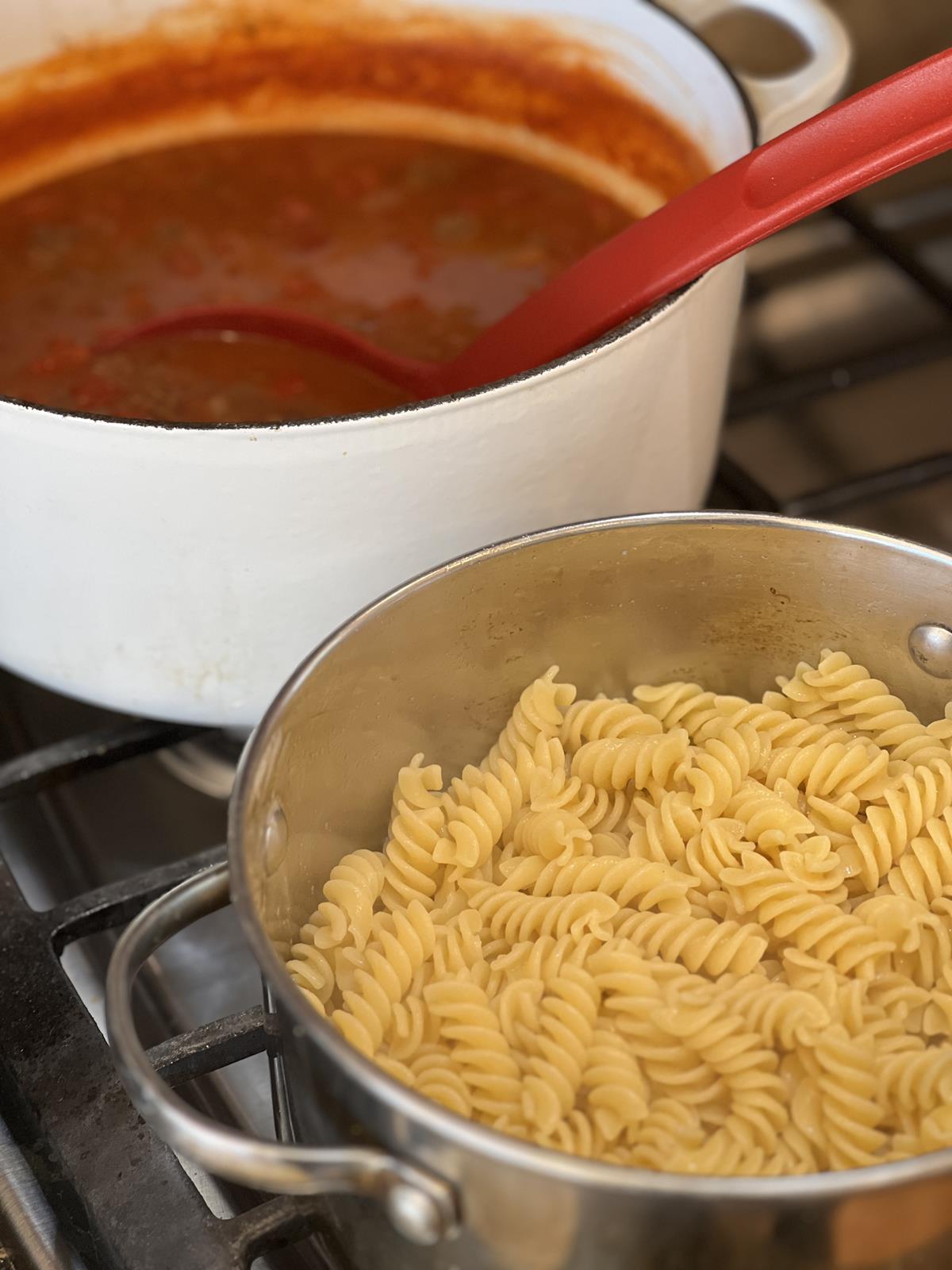 noodle in pan and sauce in white pan on stove top