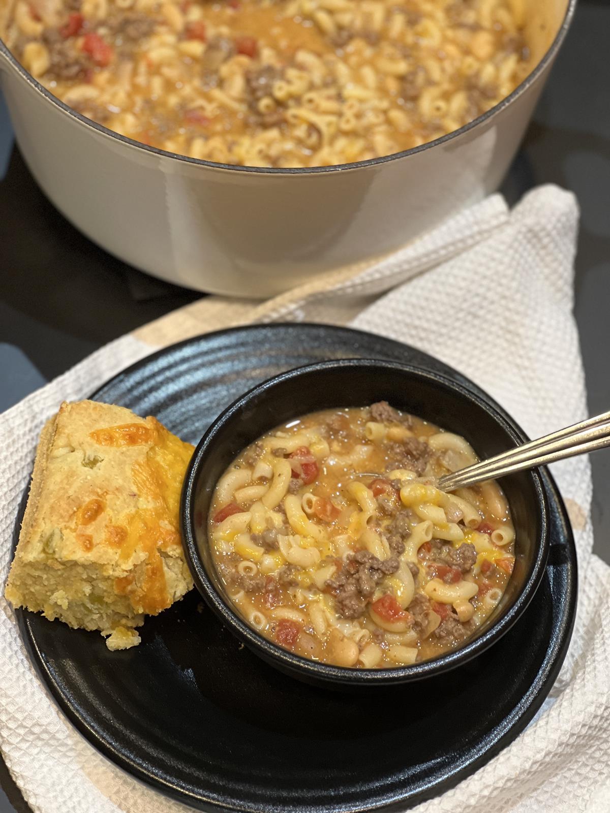 Mac and Cheese Chili in black bowl and black plate with cast iron pot in background