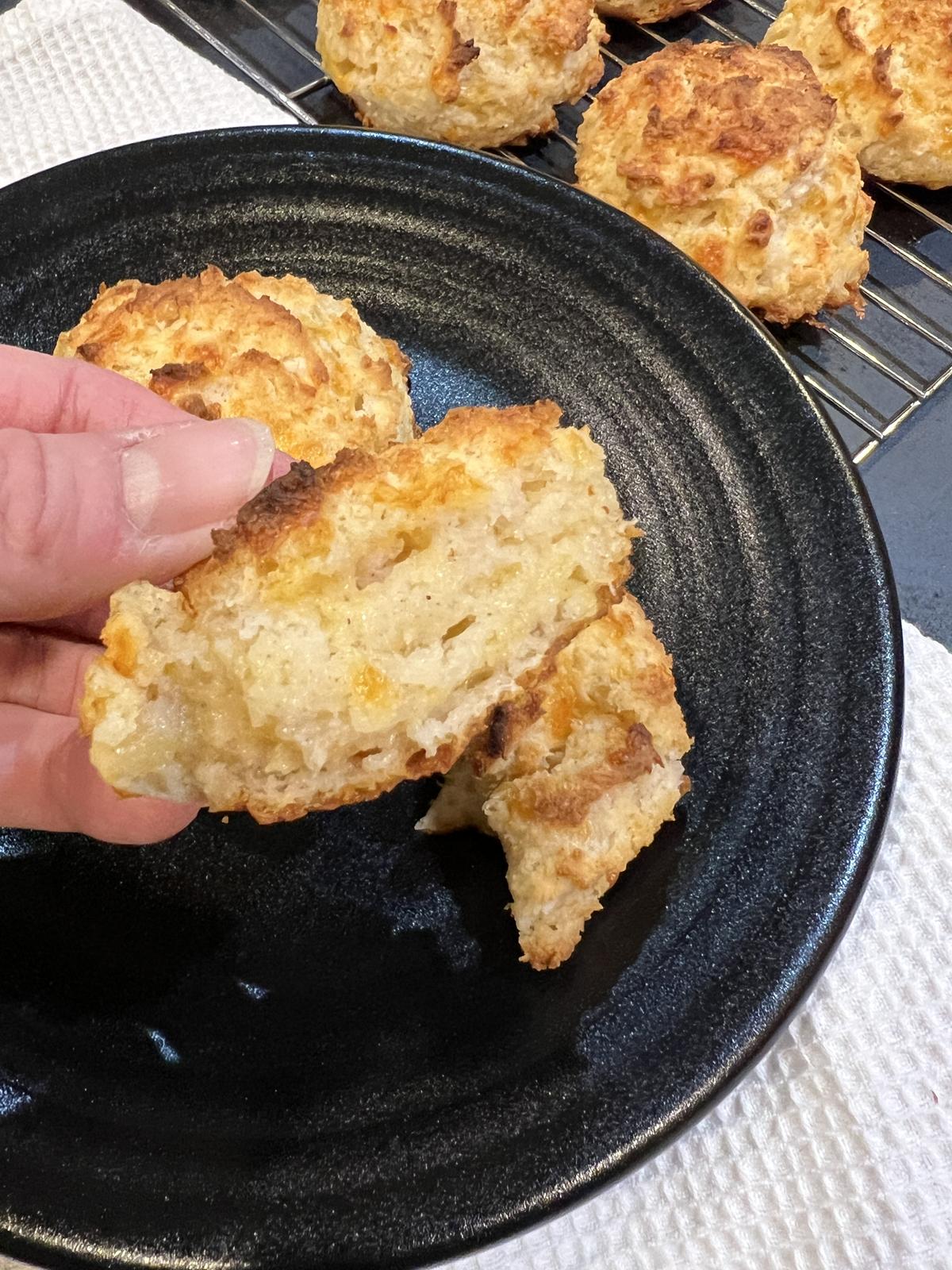 Gluten Free Cheddar Bay Biscuit on black plate with hand holding biscuit