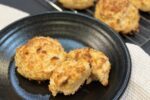 cheddar biscuits on black plate on white napkin with cooling rack in background