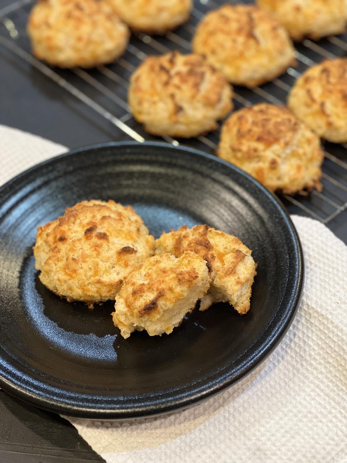 cheddar biscuits on black plate on white napkin with cooling rack in background