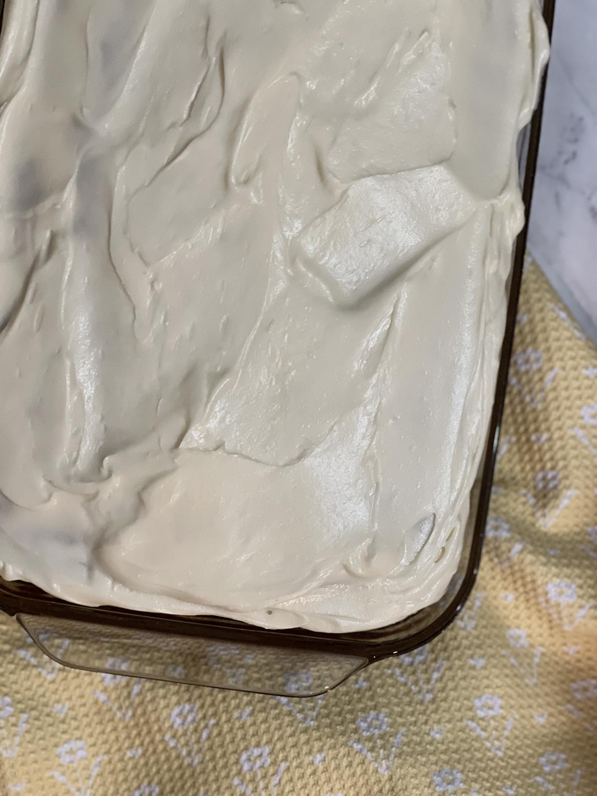 cake with frosting in glass pan on yellow and white napkin