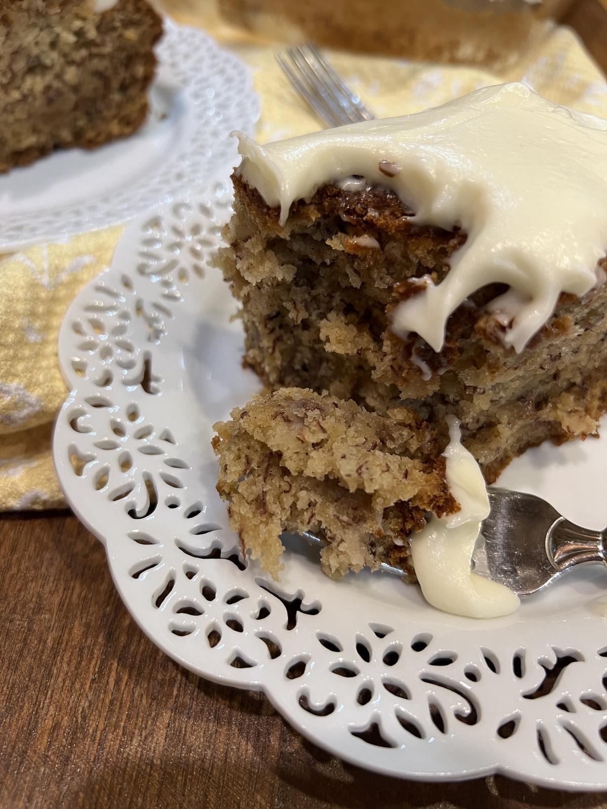 banana cake with frosting on white plate with fork