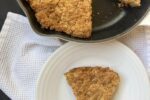 Gluten Free Soda Bread with Cheese Recipe on white plate with cast iron pan with bread in it in background