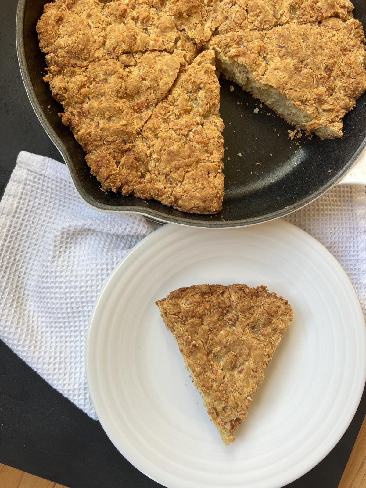 Gluten Free Soda Bread with Cheese Recipe on white plate with cast iron pan with bread in it in background