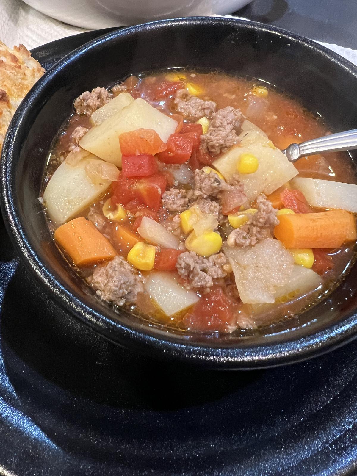 ground beef stew in black bowl with spoon