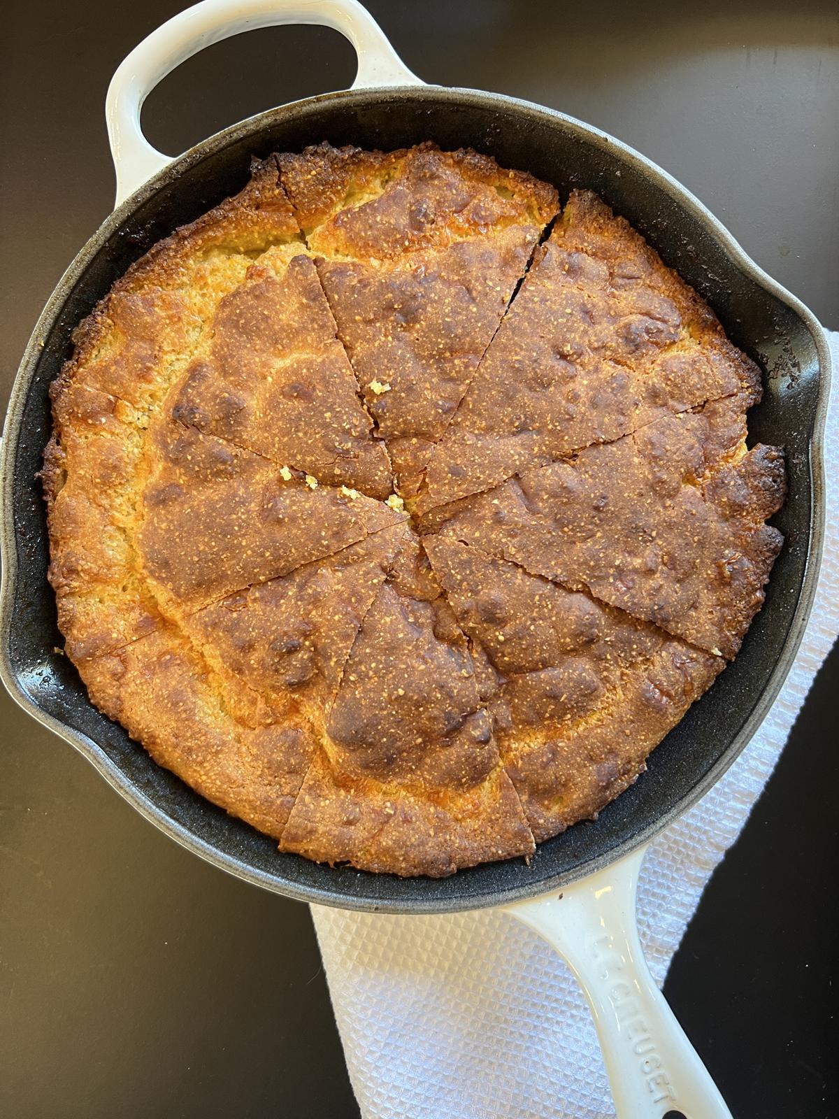 cheddar cornbread in cast iron pan on white cloth